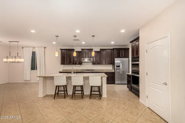 a large kitchen with kitchen island a large counter top stainless steel appliances and cabinets