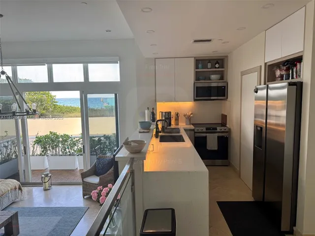 a kitchen with stainless steel appliances a refrigerator a stove a sink a dining table and chairs with wooden floor