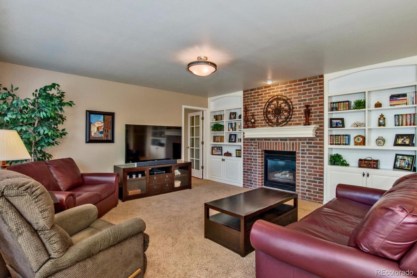 1757 Spring Water Place Highlands Ranch, CO 80129 - Photo 11 of 34 a living room with furniture a flat screen tv and a fireplace