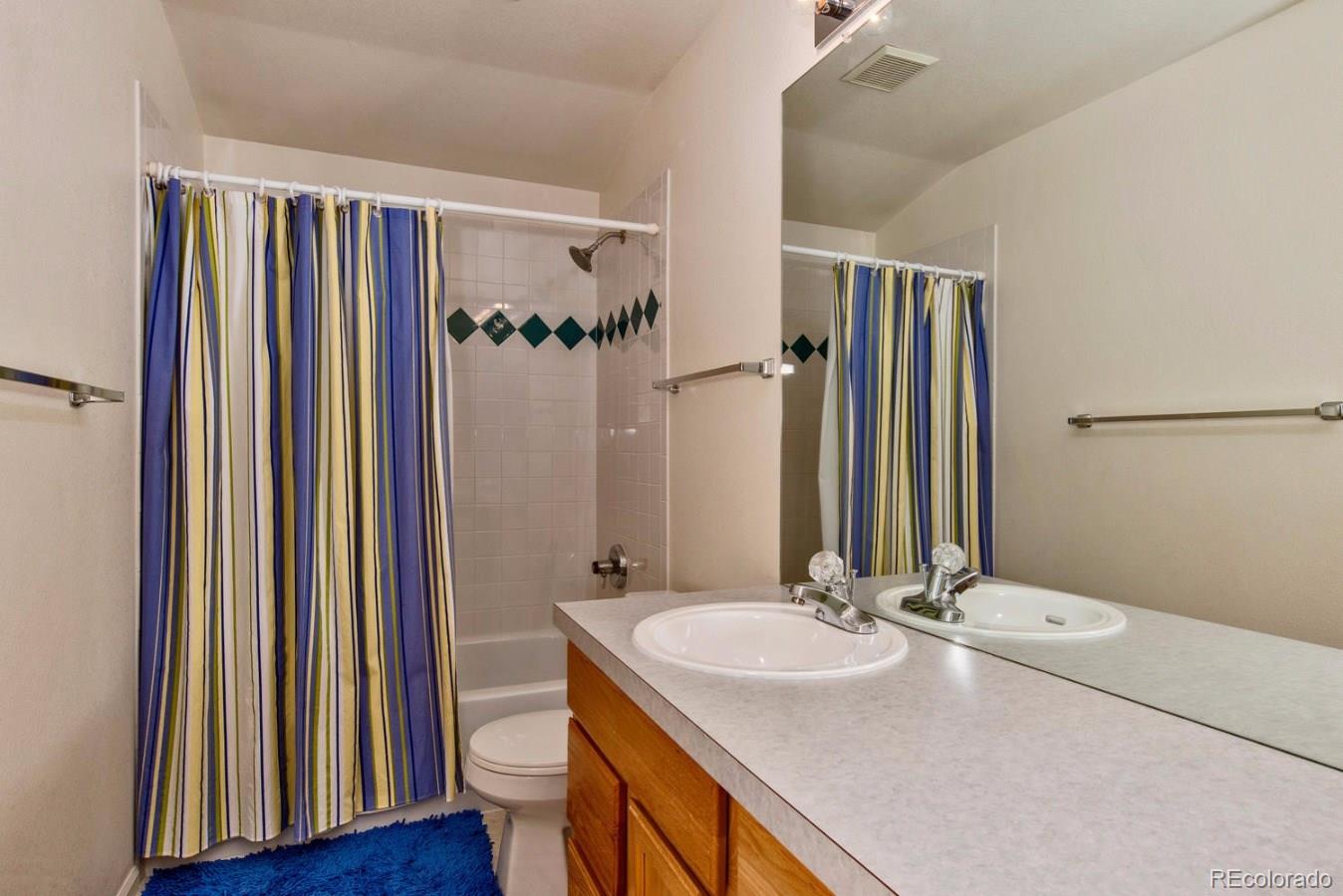 1757 Spring Water Place Highlands Ranch, CO 80129 - Photo 21 of 34 a bathroom with a sink a toilet a mirror and shower curtain