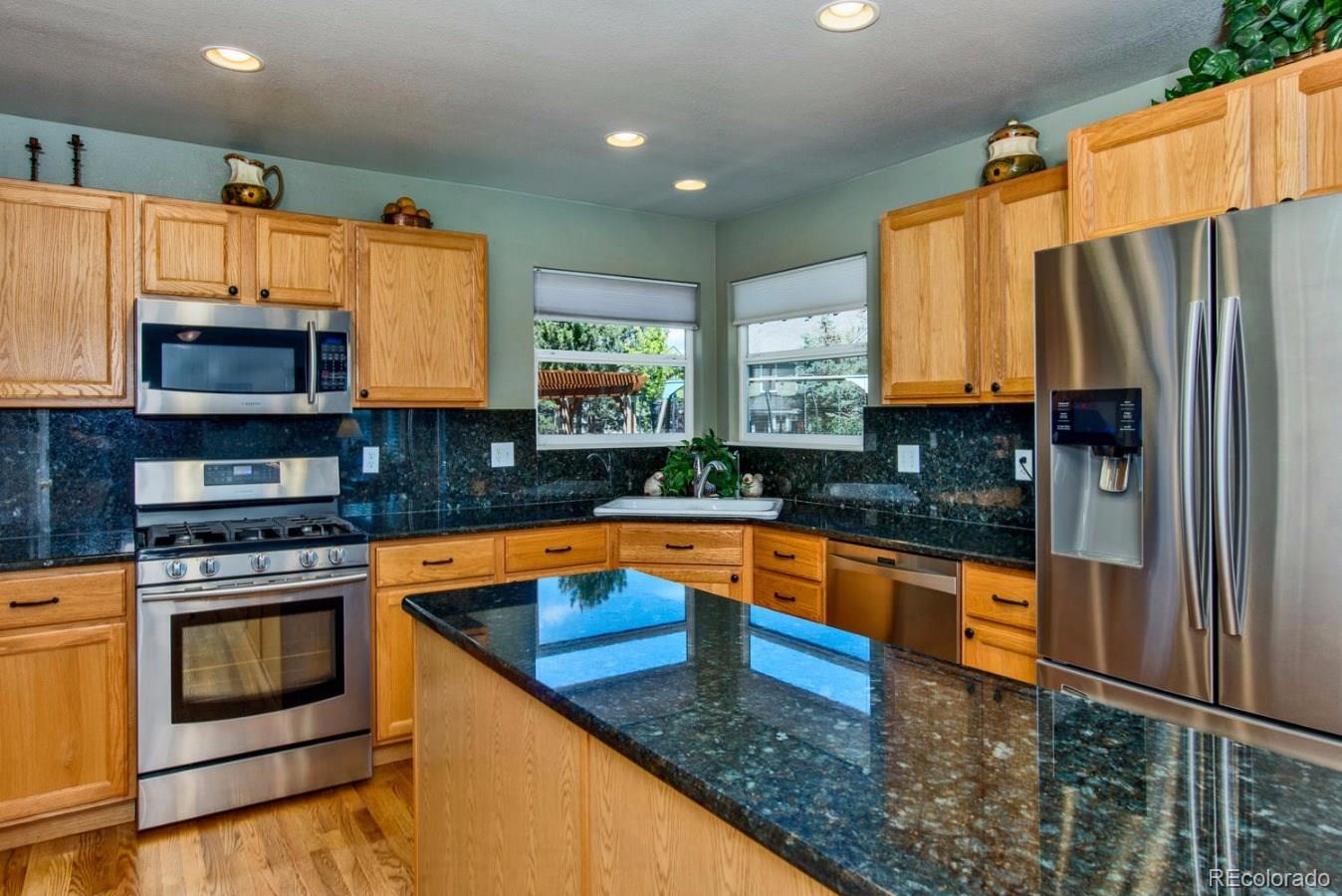 1757 Spring Water Place Highlands Ranch, CO 80129 - Photo 7 of 34 a kitchen with stainless steel appliances granite countertop a stove a sink and a microwave