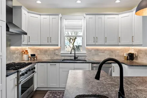 a kitchen with stainless steel appliances granite countertop a stove a sink and a microwave
