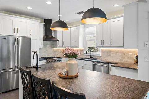 a kitchen with stainless steel appliances granite countertop a sink a stove and refrigerator