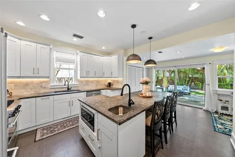 a kitchen with granite countertop a stove a sink a kitchen island with chairs and wooden floor