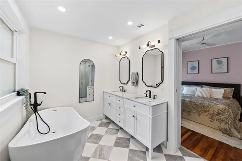 a bathroom with a double vanity sink mirror and bathtub