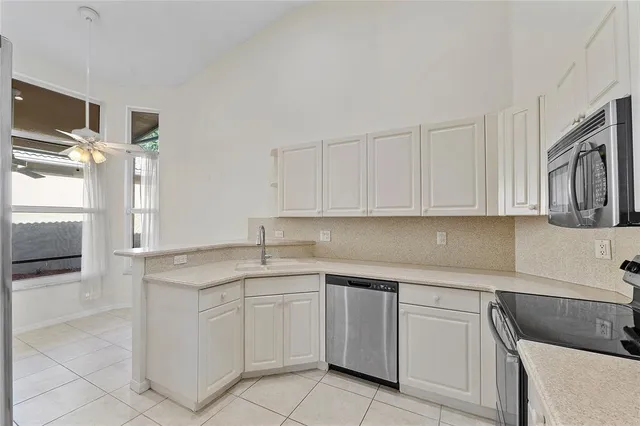 a kitchen with white cabinets appliances a sink and a counter top space