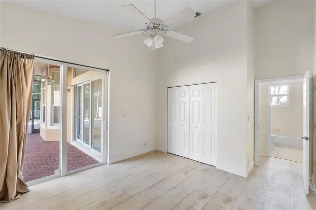 an empty room with wooden floor and a ceiling fan