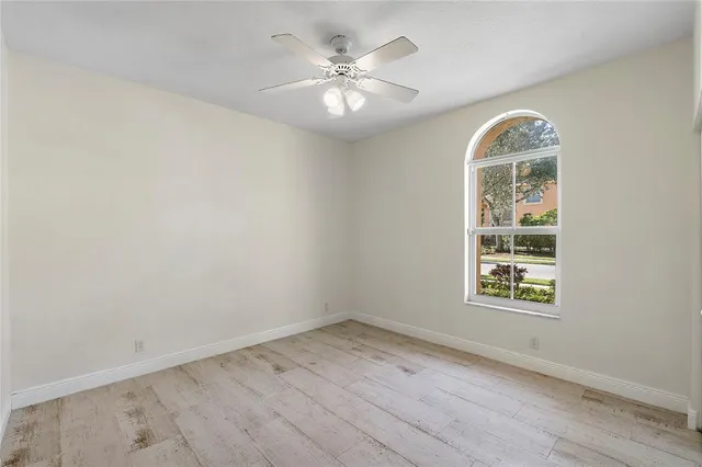 an empty room with wooden floor chandelier and windows