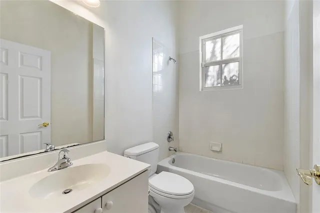 a bathroom with a bathtub shower sink vanity mirror and toilet