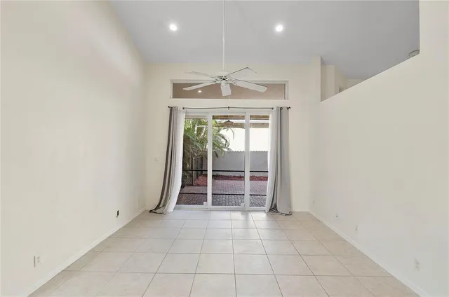 an empty room with chandelier fan and outdoor view