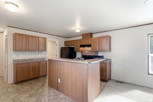 2875 North Hill Field Road, Unit 62 Layton, UT 84041 - Photo 12 of 34 Kitchen featuring wood-finish cabinetry, dark countertops, and a mosaic tile backsplash