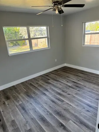 a view of an empty room with wooden floor and windows