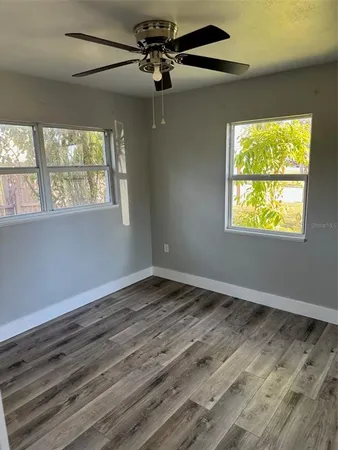 a view of an empty room with wooden floor and a window