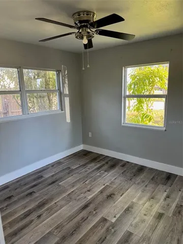 a view of an empty room with wooden floor and a window