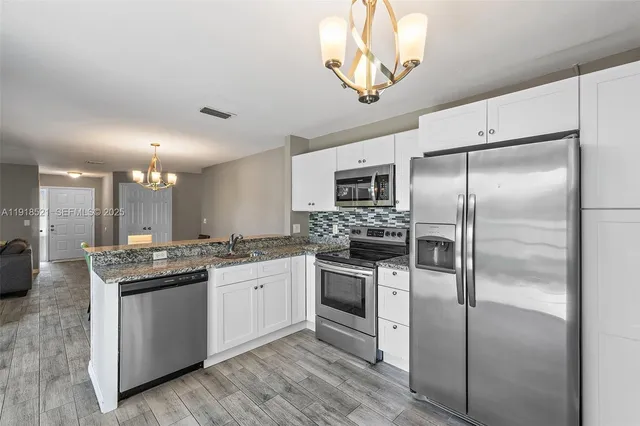 a kitchen with a sink stainless steel appliances and white cabinets