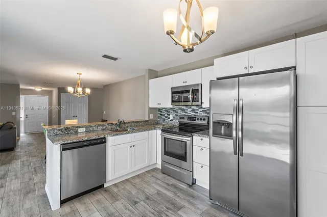 a kitchen with a sink stainless steel appliances and white cabinets