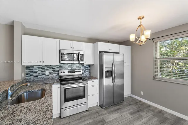 a kitchen with granite countertop a refrigerator stove and sink