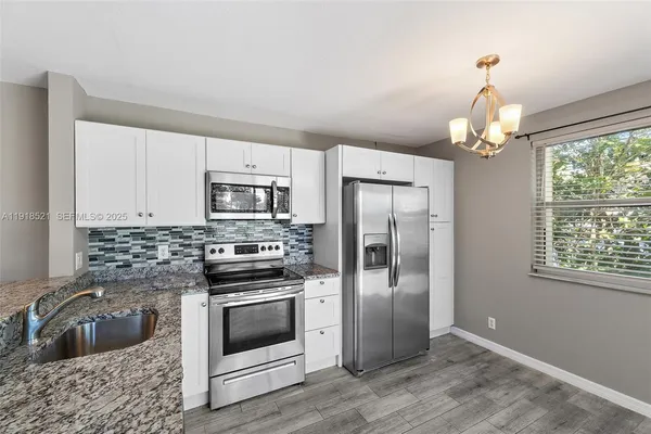 a kitchen with granite countertop a refrigerator stove and sink