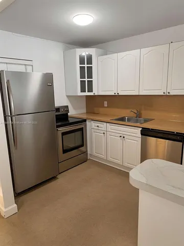 a kitchen with a sink a refrigerator and cabinets