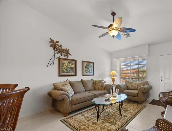 a living room with furniture a rug potted plant and a window