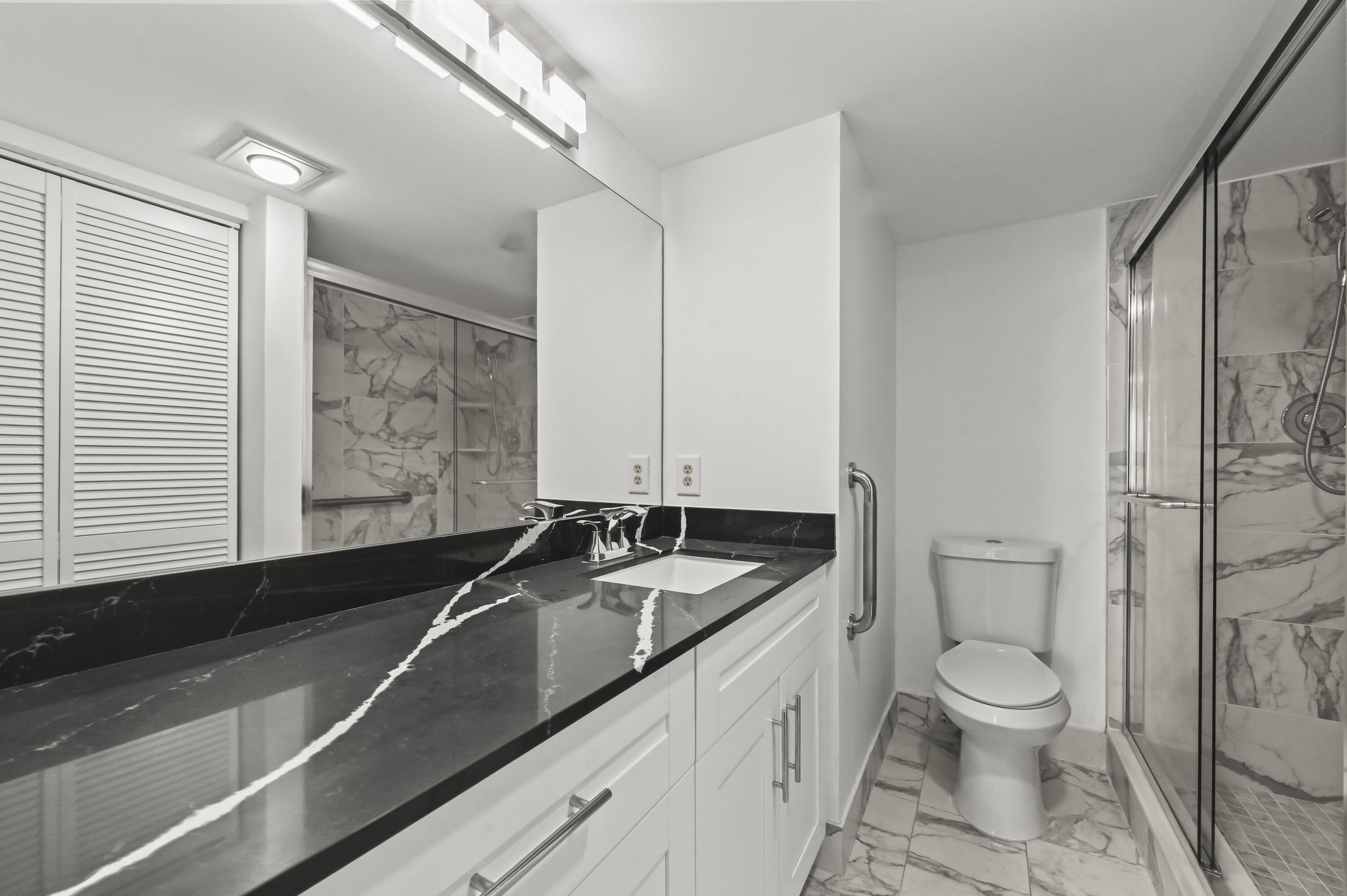 3046 Newcastle A Boca Raton, FL 33434 - Photo 19 of 25 a bathroom with a granite countertop sink a toilet and a mirror