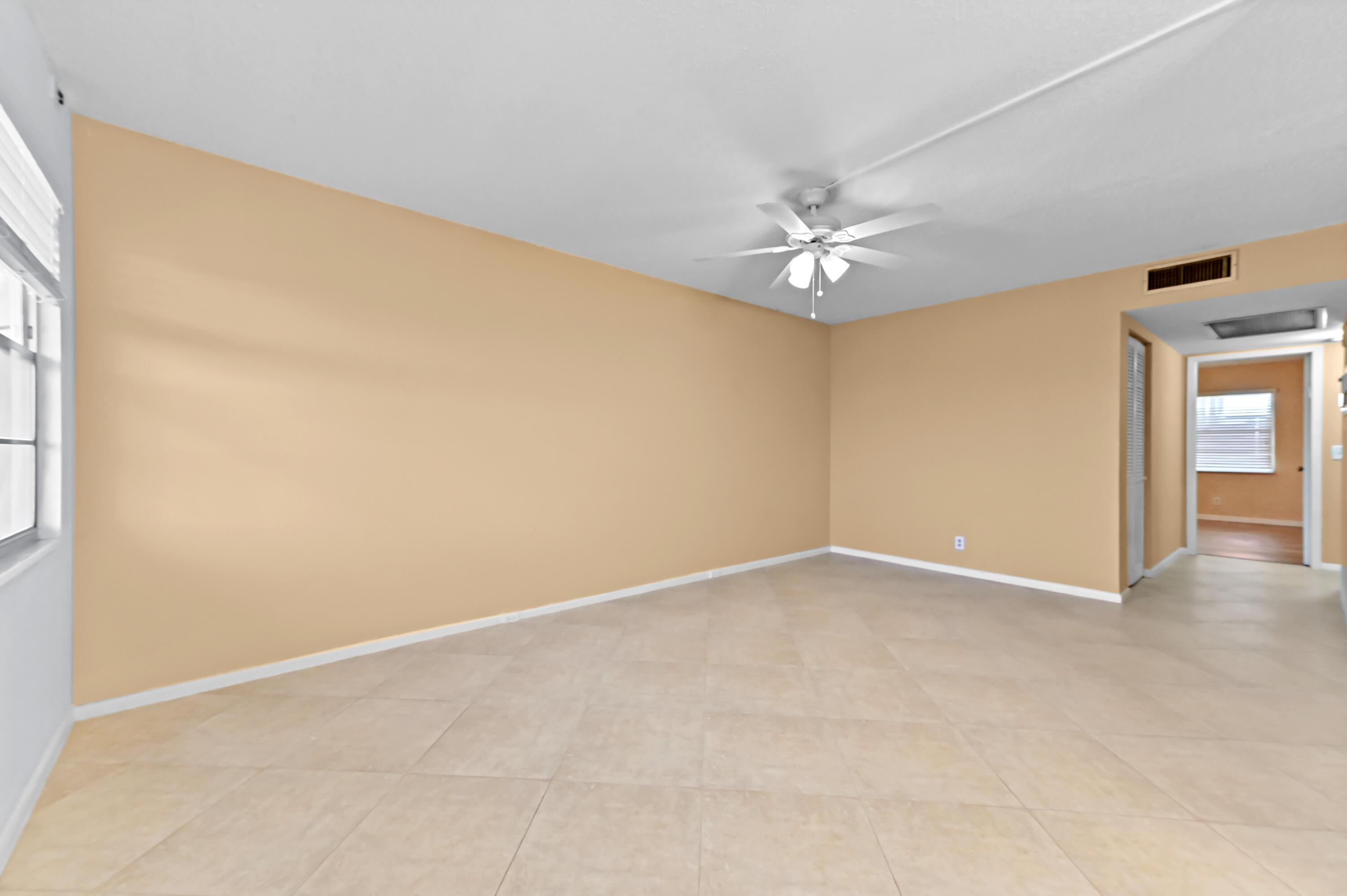 3046 Newcastle A Boca Raton, FL 33434 - Photo 6 of 25 an empty room with a chandelier fan and windows