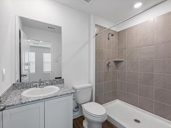 a bathroom with a granite countertop sink a toilet and shower