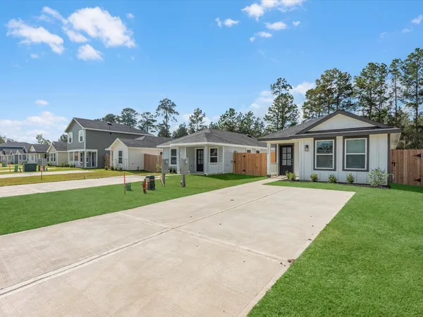 a view of a house next to a big yard with plants and large trees