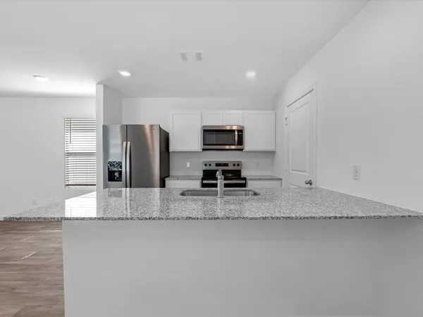 a view of a kitchen with a sink a counter top space cabinets and stainless steel appliances