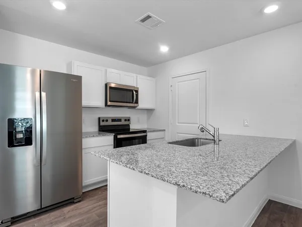 a kitchen with granite countertop a refrigerator a stove and a sink
