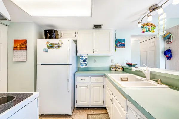 a kitchen with stainless steel appliances a refrigerator a stove a sink and white cabinets with wooden floor