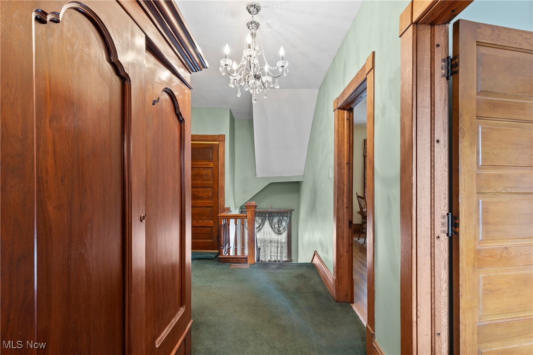 1011 Parriott Avenue Moundsville, WV 26041 - Photo 20 of 44 Hallway featuring an upstairs landing, a chandelier, and dark carpet