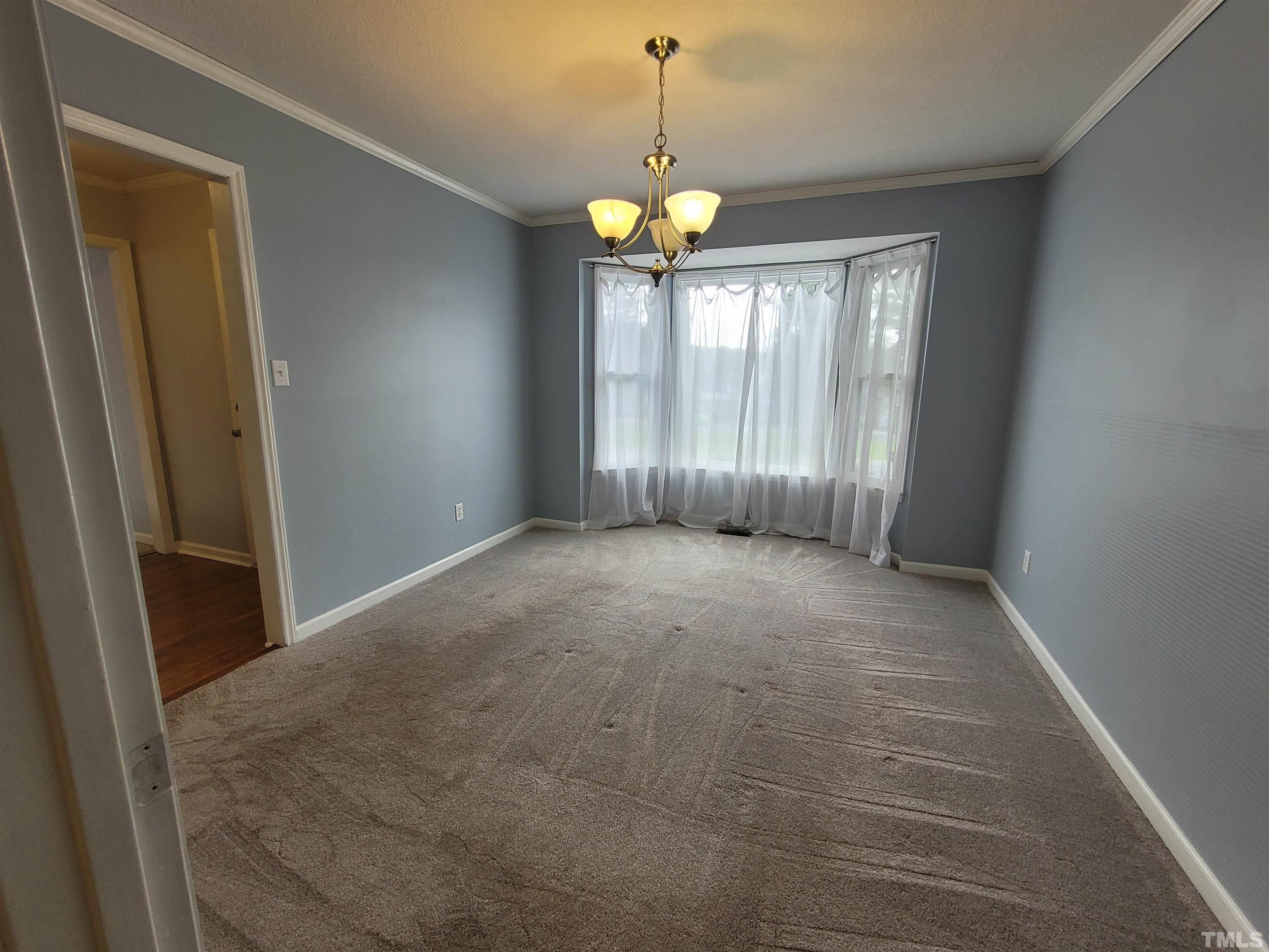 4836 Draper Road Raleigh, NC 27616 - Photo 7 of 16 a view of an empty room with window and chandelier