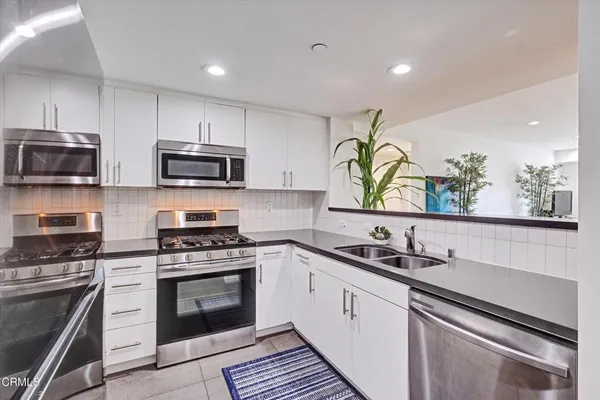 a kitchen with stainless steel appliances white cabinets white stove a refrigerator and a microwave