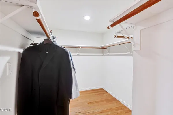 a view of a hallway with wooden floor and a bathroom