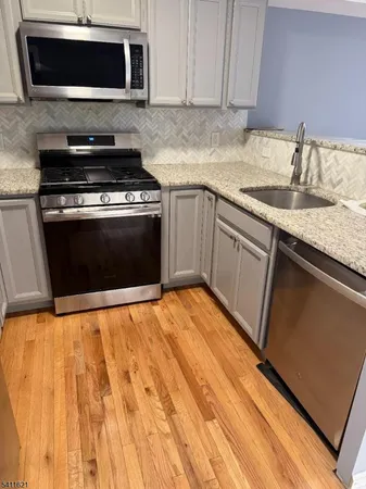 a kitchen with granite countertop a stove top oven microwave and sink