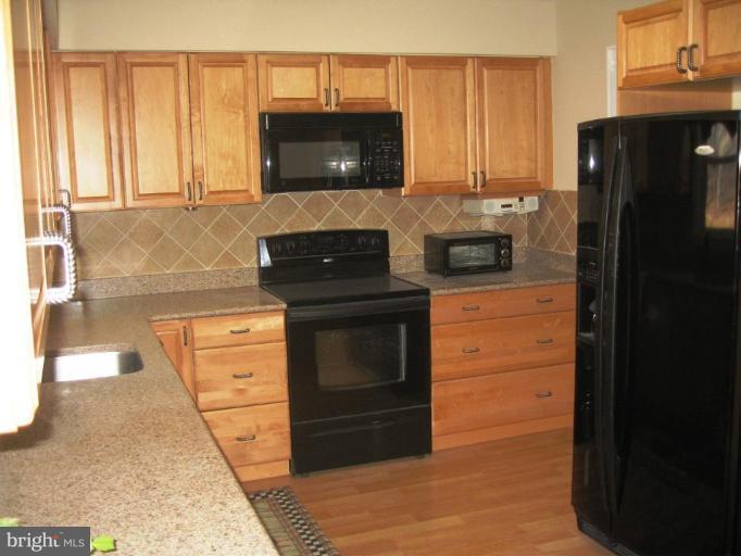 6278 Rathlin Drive Springfield, VA 22152 - Photo 12 of 25 a kitchen with granite countertop white cabinets and black appliances