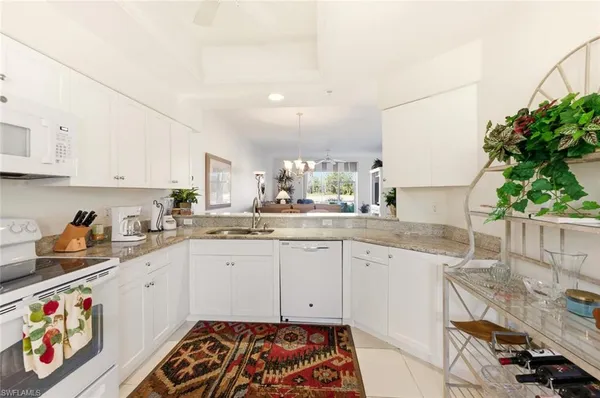 a kitchen with granite countertop lots of white stainless steel appliances granite countertop a sink and a refrigerator