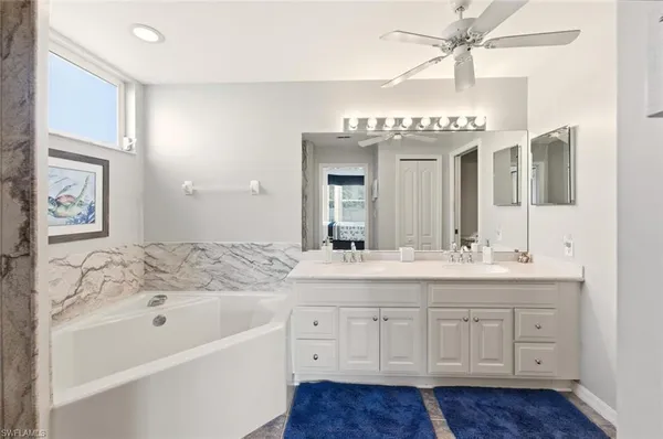 a bathroom with a tub a double vanity sink and a mirror