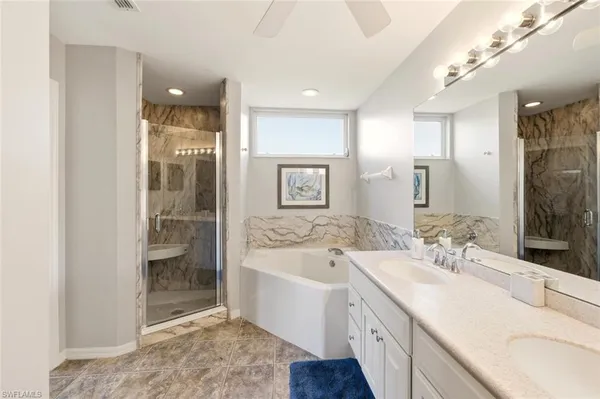 a spacious bathroom with a bathtub shower sink mirror and toilet