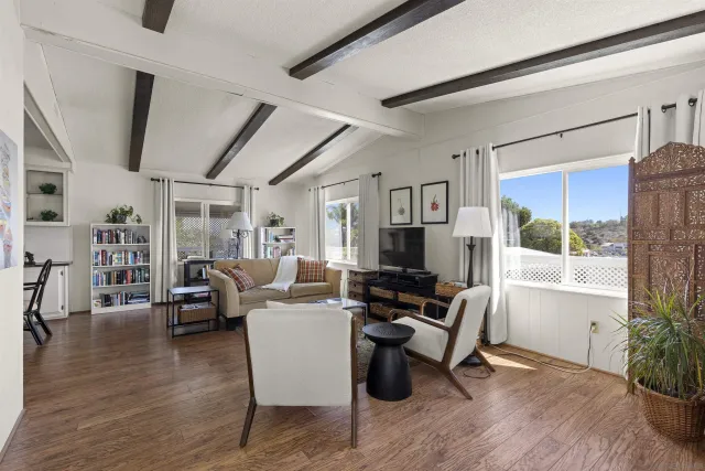 a living room with furniture floor to ceiling window and wooden floor