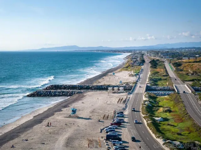 an aerial view of ocean and residential houses with outdoor space