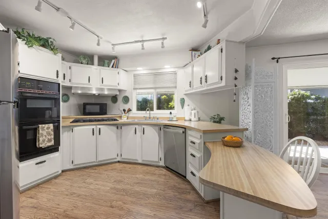 a kitchen with stainless steel appliances granite countertop a sink a stove a microwave a refrigerator cabinets and living room view