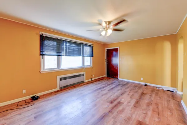 a view of an empty room with a window and wooden floor