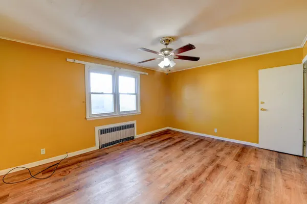a view of an empty room with a window and wooden floor