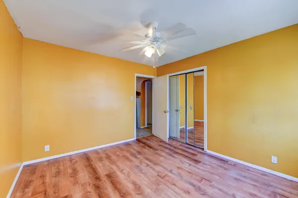 a view of a big room with wooden floor and chandelier fan