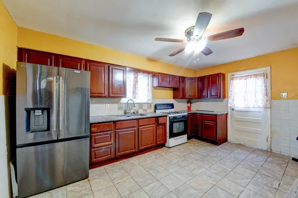 a kitchen with stainless steel appliances granite countertop a refrigerator a sink dishwasher a stove with wooden cabinets and floor