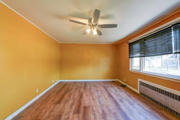 a view of empty room with wooden floor and fan