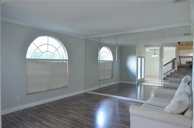 a view of a room with wooden floor a chandelier fan and closet