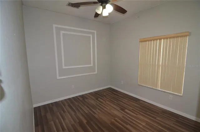a view of a room with wooden floor and a ceiling fan